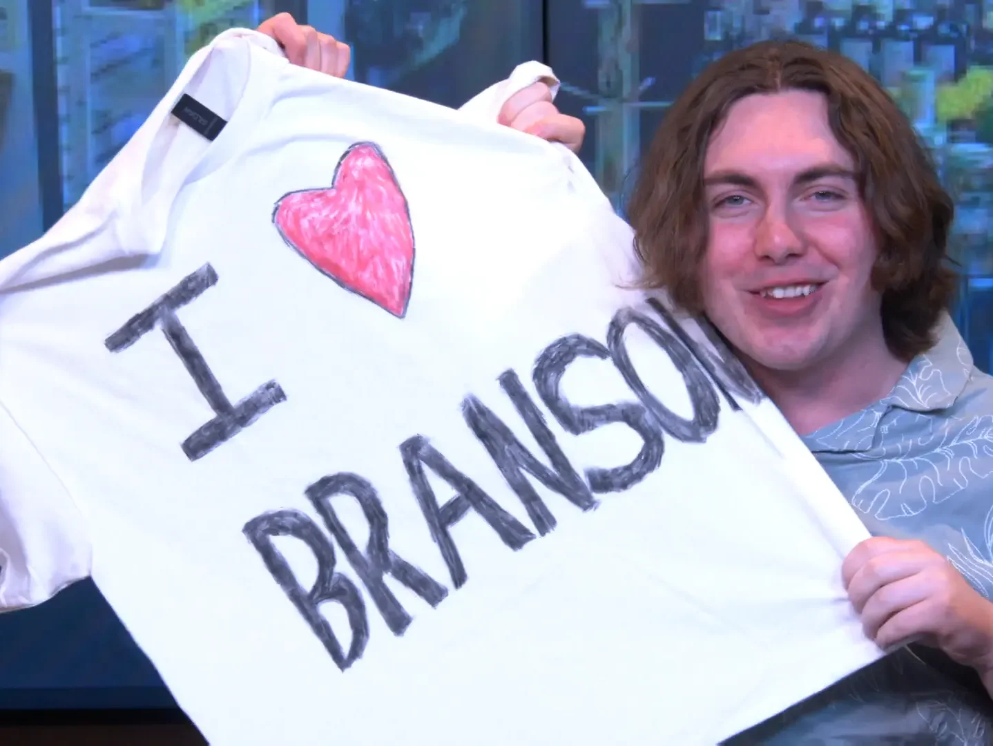 A young man holds up a t-shirt with the words ‘I ♥ Branson’ written on it