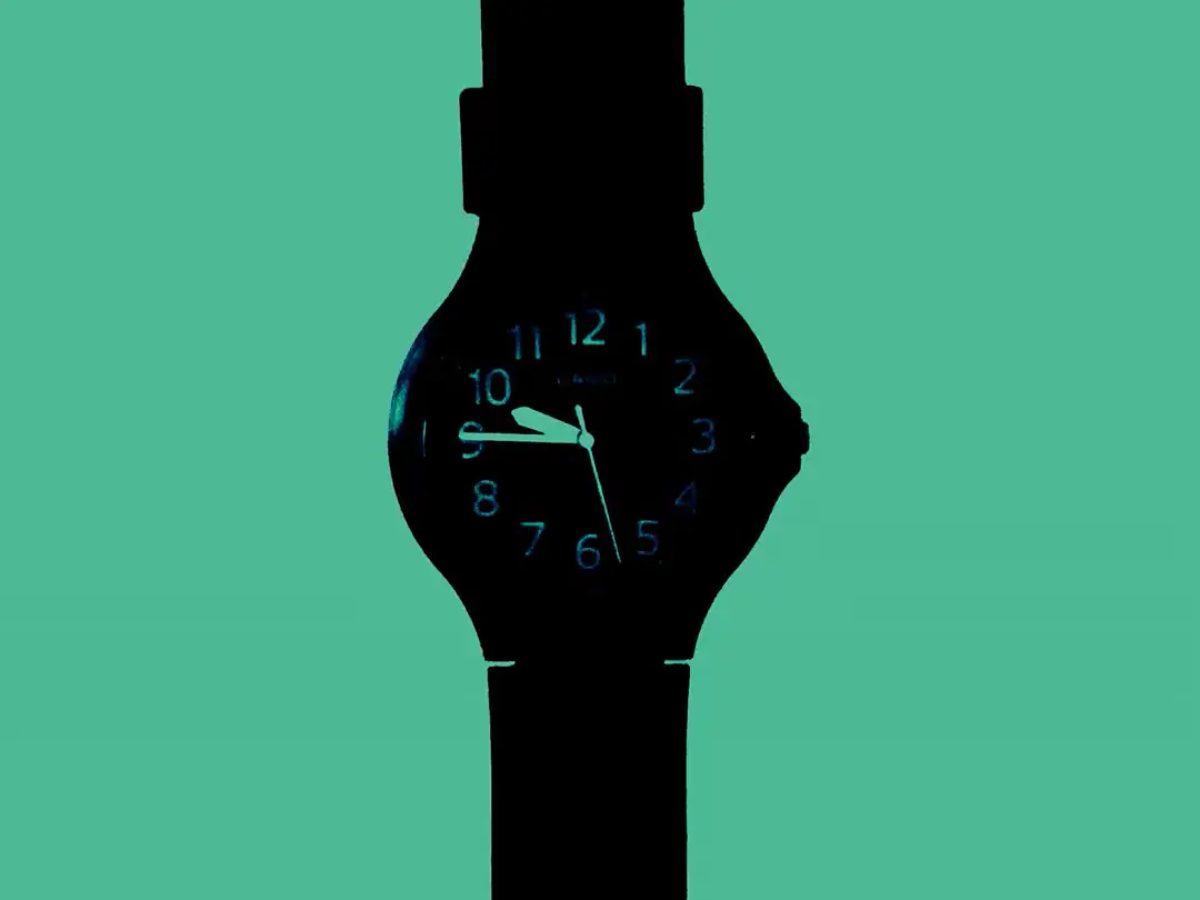 A black wristwatch showing the time at 9:45 on a green background
