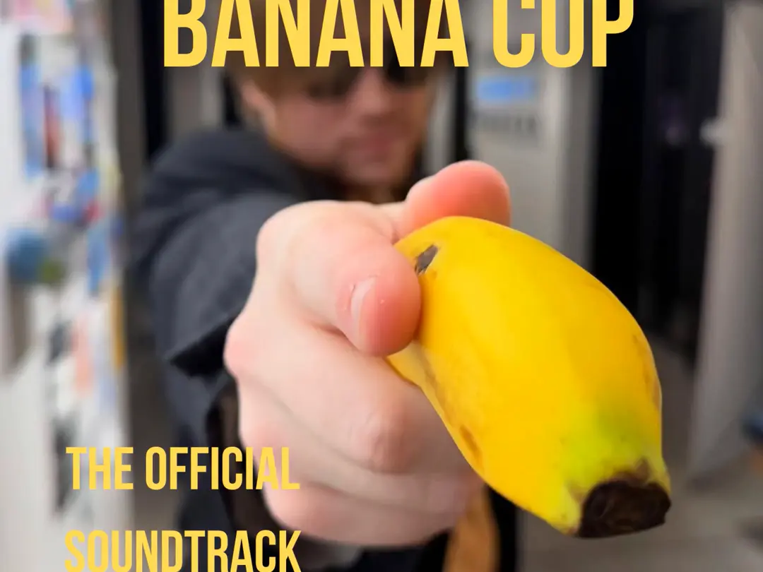 A man holding a banana in a police uniform points it at the viewer with the words “Banana Cop” written on top & “The Official Soundtrack” written below